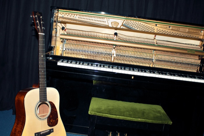 Guitarra acústica junto al interior del piano de cola
