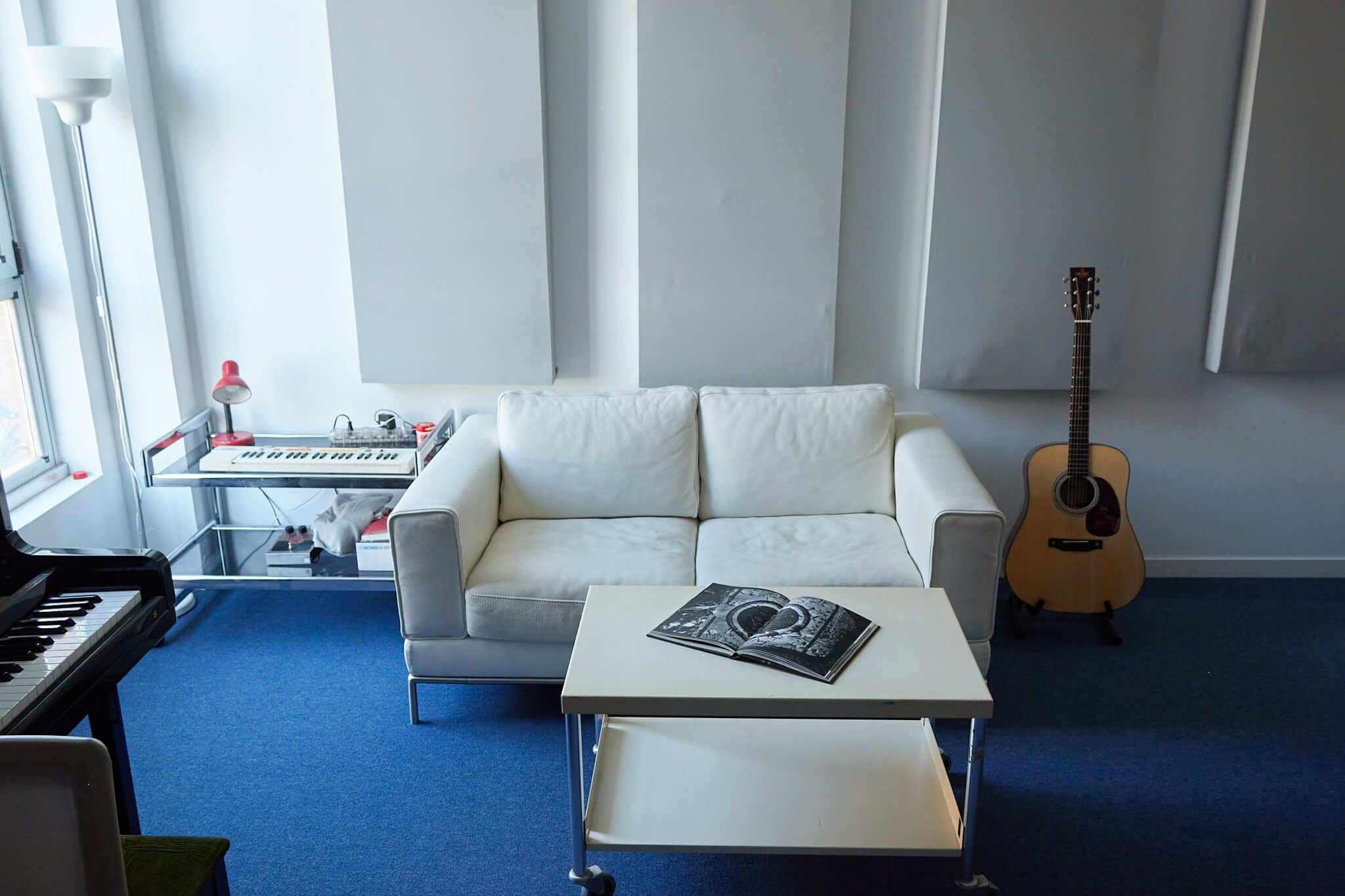 Zona de descanso del Estudio A con sofá, guitarra y mesa de centro